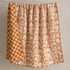 Detail of reversible side of Marigold linen quilt showing hand-block printed checkerboard pattern in terracotta and natural tones