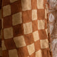 Marigold reversible linen quilt folded on bed showing both botanical and checkerboard hand-block printed sides